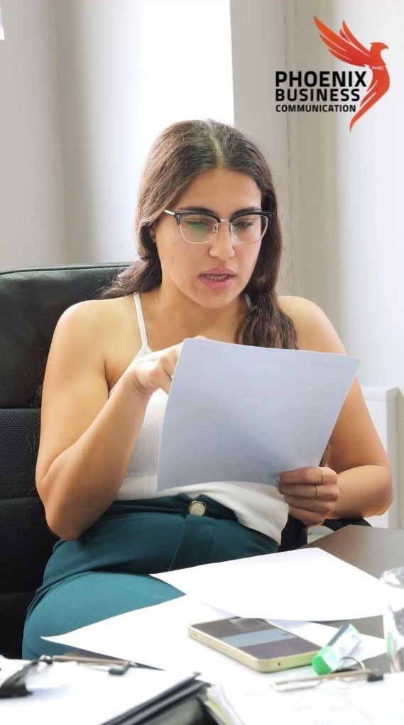 Woman wearing glasses reading a document, with 'Phoenix Business Communication' logo in the background.