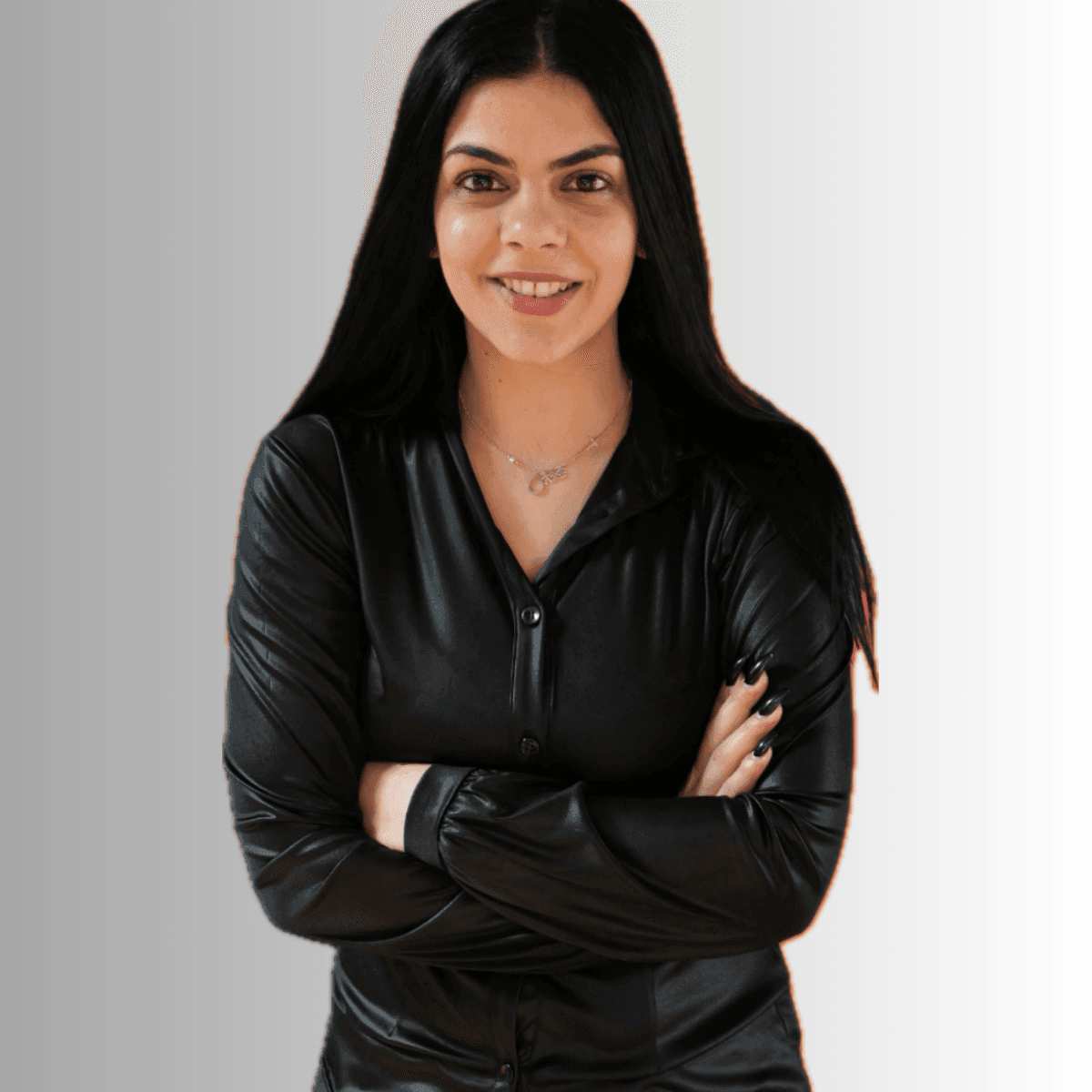 Woman in black leather shirt smiling and crossing arms against a gray background.