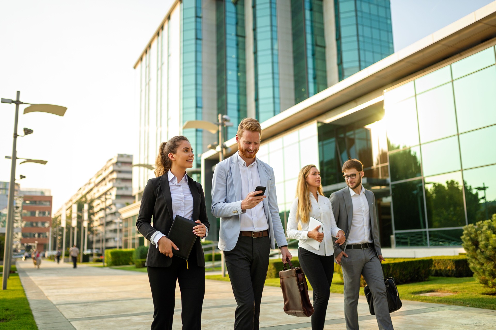 Group of cheerful young business people talking to each other while walking outdoors